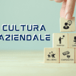 la scritta Cultura aziendale mostra una mano con dei cubi in legno con scritto sopra vari punti cruciali come wellbeing, purpose compensation